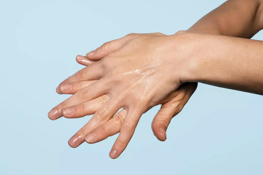 Mani di donna mentre si mette la crema per curare la pelle secca